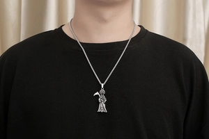 Detailed view of vintage Grim Reaper pendant with scythe on a thick braided chain