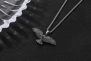 Gros plan détaillé du pendentif aigle avec plumes texturées et chaîne en acier