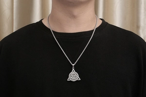 Close-up of silver Viking triangle knot pendant with intricate celtic engravings on a mesh chain