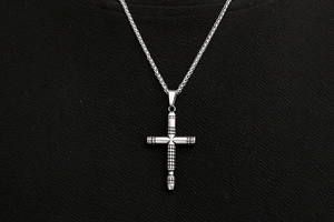 Macro view of silver titanium steel cross pendant with industrial grid texture