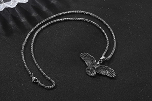 Gros plan détaillé du pendentif aigle avec texture de plumes et chaîne en métal tressé
