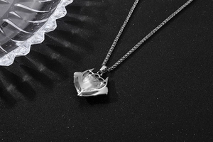 Détail d'un pendentif tête de renard argenté avec gravures fines et chaîne tressée