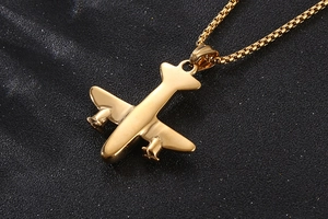 Gros plan du collier pendentif avion doré poli sur fond texturé noir élégant
