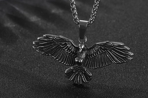 Détail macro du pendentif aigle montrant les textures d'acier et les gravures de plumes
