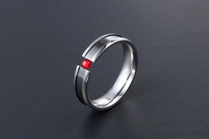 Detailed view of polished steel ring with red gemstone and black enamel inlay