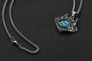 Gros plan d'un pendentif démon gothique avec œil bleu et chaîne en acier inoxydable robuste