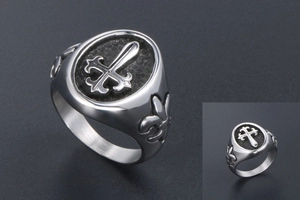 Macro detail of gothic cross ring showing fleur-de-lis engraving and matte titanium steel