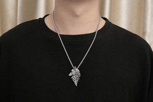 Gros plan du pendentif tête de loup argenté au style tribal porté par un homme sur fond noir