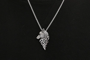 Gros plan détaillé d'un pendentif tête de loup argenté avec motifs géométriques et chaîne