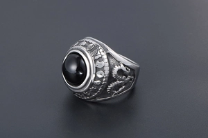 Macro shot of vintage titanium steel ring with black agate and embossed ram head details