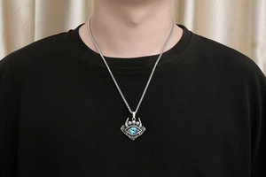 Détail du pendentif œil du diable gothique avec pupille bleue et crânes sur chaîne épi