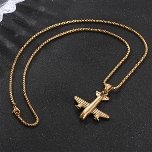 Collier en acier inoxydable doré avec pendentif avion et chaîne box sur fond noir texturé