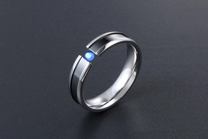 Detail of a titanium steel ring featuring a black inlay and a blue zircon tension setting