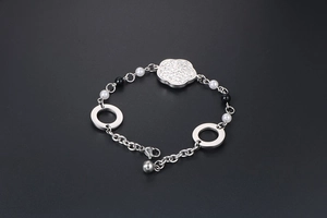 Détail du bracelet en acier titane avec pendentif fleur en zircon et perles