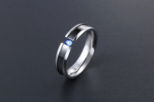 Detail of silver titanium ring with black enamel stripe and blue round gemstone inlay