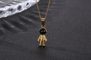 Macro shot of gold-tone astronaut pendant with black visor on a delicate link chain