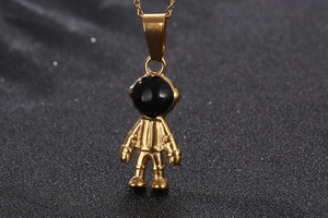 Detailed view of a gold-toned astronaut pendant with black drip oil on a dark surface