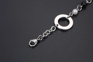 Macro détaillée du fermoir mousqueton et du motif fleur en perle du bracelet acier