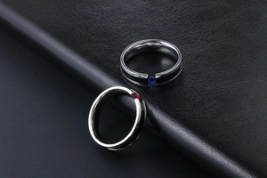 Macro shot of couple's titanium steel rings with red and blue rhinestones on leather