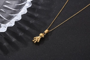 Detailed view of a golden astronaut pendant necklace on a premium black textured surface