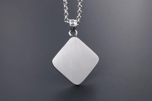 Detailed macro view of brushed titanium steel square pendant with star motif and link chain