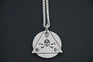 Macro detail of gothic titanium steel pendant with evil eye and skull symbols