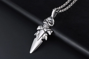 Vue macro du pendentif tête de mort et dague en acier inoxydable sur fond en cuir noir