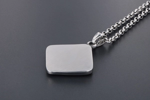Macro shot of silver titanium steel rectangular pendant with brushed matte finish and rolo chain