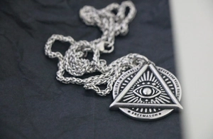 Macro shot of retro stainless steel pendant with eye of providence and engraved text