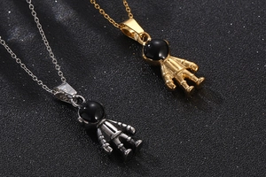 Macro shot of gold and silver astronaut pendants with black enamel visors on space backdrop