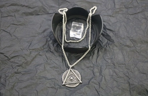 Macro shot of silver retro triangular All-Seeing Eye pendant and stainless steel chain