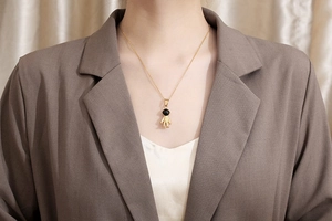 Close-up of golden astronaut pendant necklace worn by model on a brown blazer