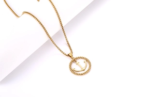 Détail du pendentif ancre dorée dans un cercle torsadé sur une chaîne fine