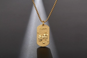 Makroaufnahme des goldenen Zwilling-Anhängers mit Textur und geprägtem Maskendetail