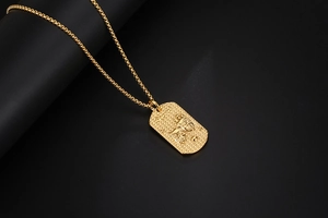 Makro-Detail des goldenen Zwillinge-Anhängers mit Theatermasken und Box-Kette