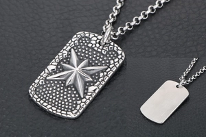 Detail of vintage silver dog tag pendant featuring compass star on leather background