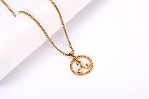 Detailed view of golden triskelion pendant with braided texture and brushed metal finish