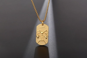 Detailed view of a gold Libra zodiac pendant with textured finish on a ball chain