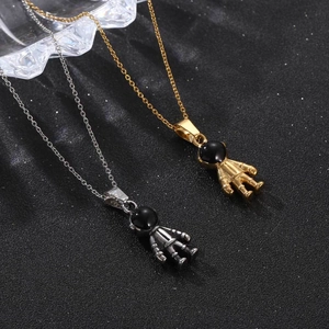 Gold and silver robot astronaut pendant necklaces with black astronaut helmets on sand