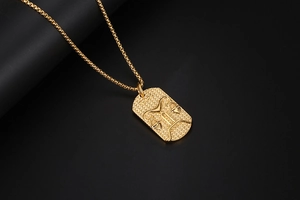 Macro detail of gold Libra zodiac pendant with embossed relief and polished box chain