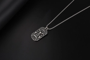 Macro shot of silver Libra pendant with textured finish and square pearl chain necklace
