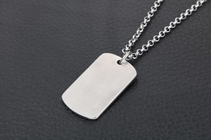 Close-up of military dog tag pendant in brushed silver steel on black leather background