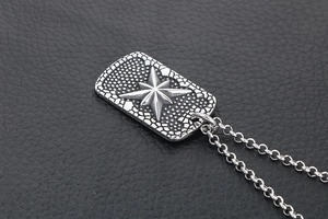 Macro detail of silver titanium steel dog tag necklace with embossed star on leather