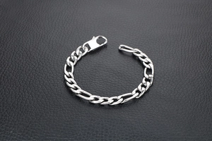 Detailed close-up of a silver titanium steel Figaro chain bracelet with a lobster clasp