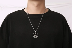 Close-up of titanium steel triskelion pendant necklace worn on black t-shirt