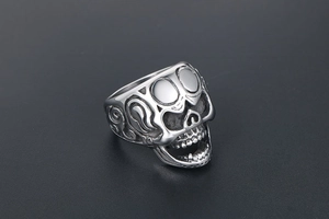 Détail macro d'une bague tête de mort gothique avec gravures de vigne et finition argentée