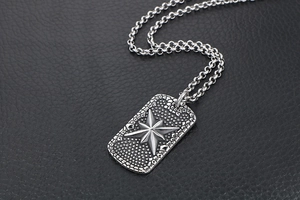 Macro shot of industrial titanium steel dog tag pendant with raised star and textured finish