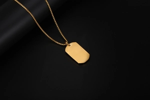 Detailed close-up of a polished gold Libra zodiac tag pendant with a wheat chain on black