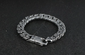 Macro shot of vintage stainless steel Cuban link bracelet with engraved floral patterns