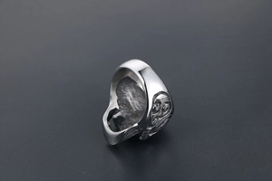Détail de la bague tête de mort argentée avec motifs gothiques en relief et texture punk